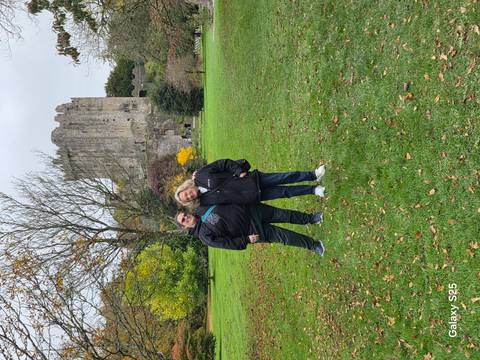 Two people standing in front of a historic stone castle, with autumn foliage.