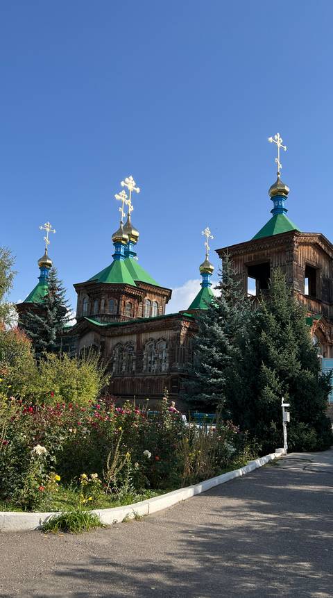       Wooden church with vibrant golden and blue domes.
  