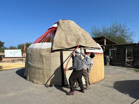       Two people setting up a traditional yurt.
  