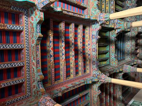       Intricately decorated wooden ceiling with colorful designs.
  