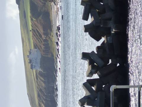       Detached building on a hill overlooking a rocky coastline.
  