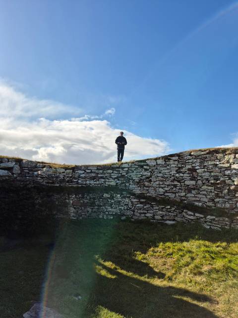       Man standing on ancient stone wall ruins.
  