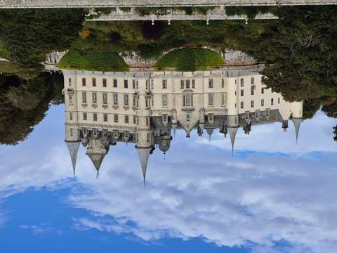       Large, historic castle set on a green hill with a cloudy sky.
  