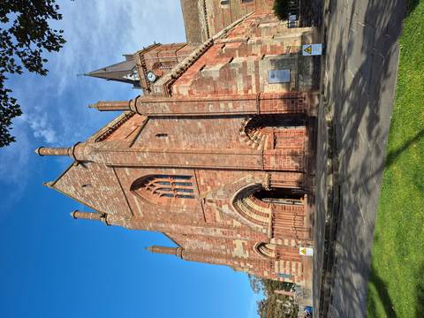 A historic cathedral with red stone architecture under a clear blue sky.