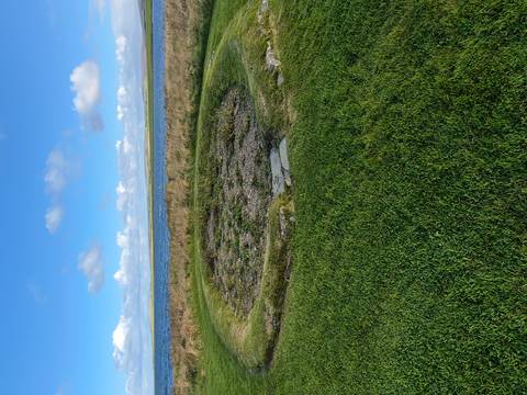 A circular stone structure possibly a historical site near the water.