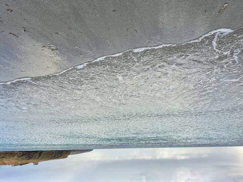 Close-up of gentle waves on a sandy beach.