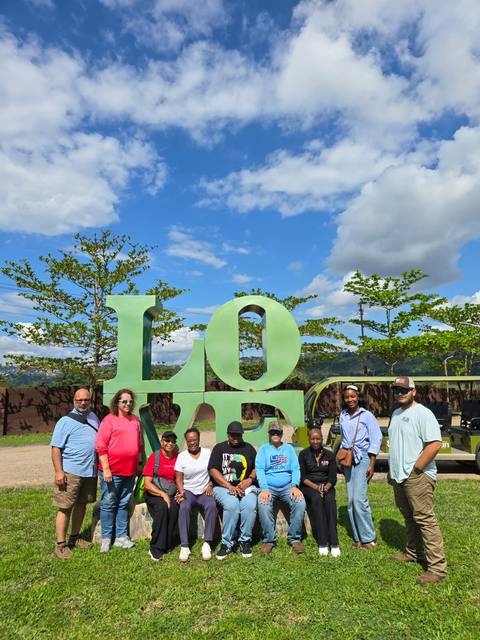 Group of people standing beside a large 'LOVE' sign.