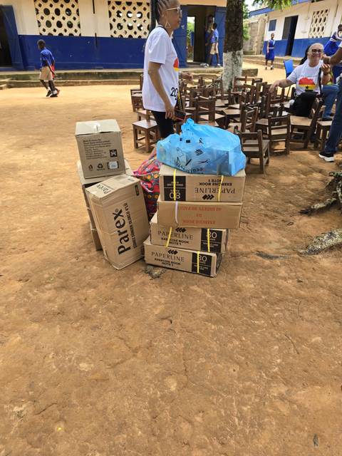 Stacked cardboard boxes and bags on a dirt surface.