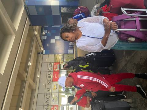 People with luggage at an airport terminal.