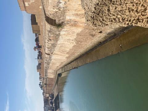 Ancient city wall beside a calm canal.
