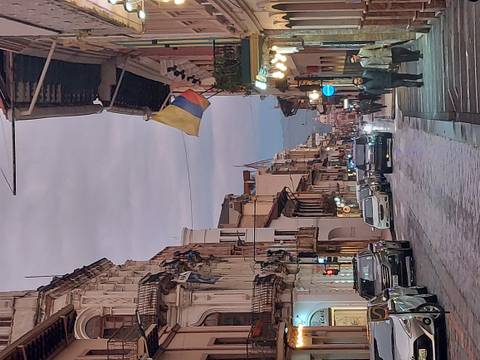 Street view in Ecuador with cars and people, and national flag.