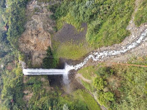 Tall waterfall cascading down rocks in a lush forested area.