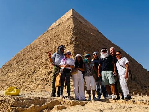 Group of people posing in front of a pyramid.