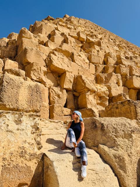 Woman sitting on large stones of a pyramid structure.