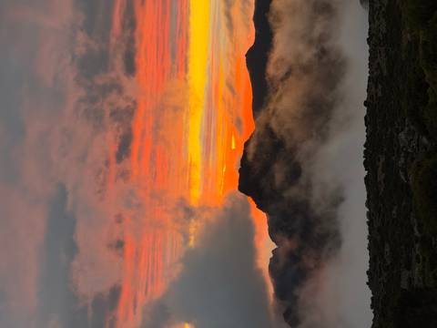       Colorful sunset over a mountainous landscape with mist.
  