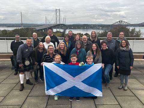 People holding a Scottish flag with a bridge and river in the background.