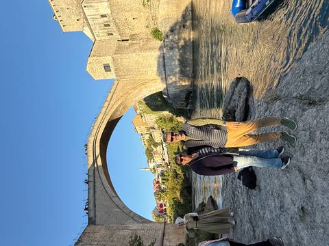 Couple posing by a historic bridge over a river.