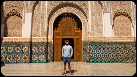 Man standing in front of an ornate mosaic and stucco building.