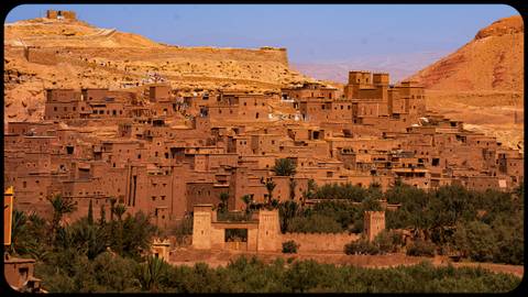 Ancient Moroccan village built of earthen clay under a blue sky.