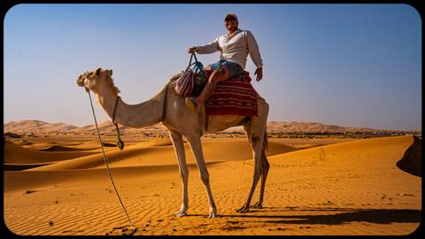 Man riding a camel in the desert.
