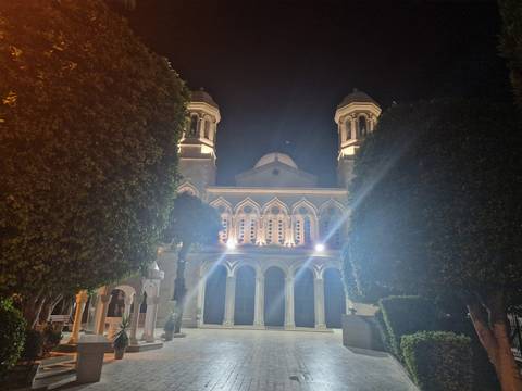 Lit church building at night with trees.