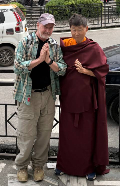       A tourist posing with a monk in traditional attire.
  