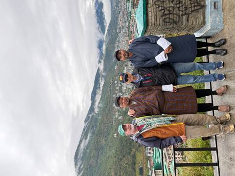       Group of tourists posing with Bhutanese locals wearing traditional dresses.
  