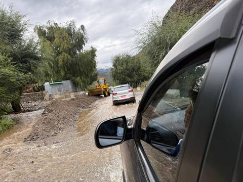       Cars navigate a muddy road with construction equipment visible.
  