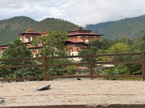       Traditional Bhutanese Dzong with red roofs and green mountains.
  