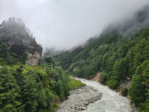 Misty valley with river flowing through forest in Nepal.