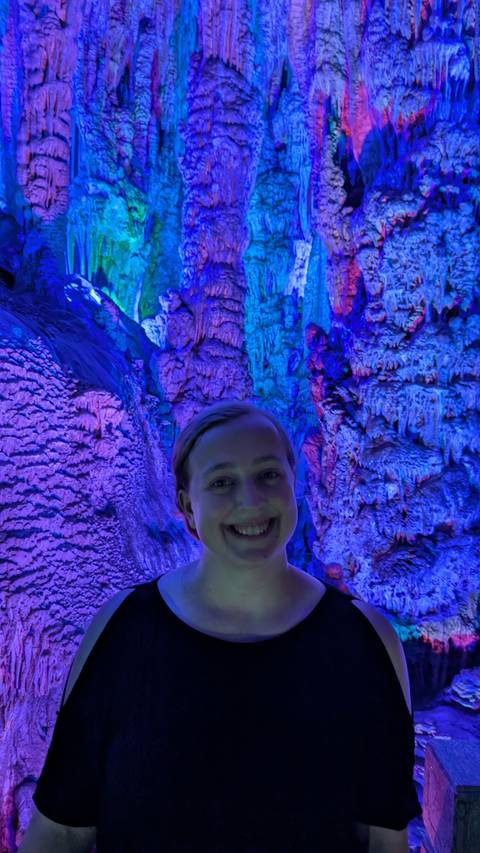       A happy person inside a cave with colorful lights.
  