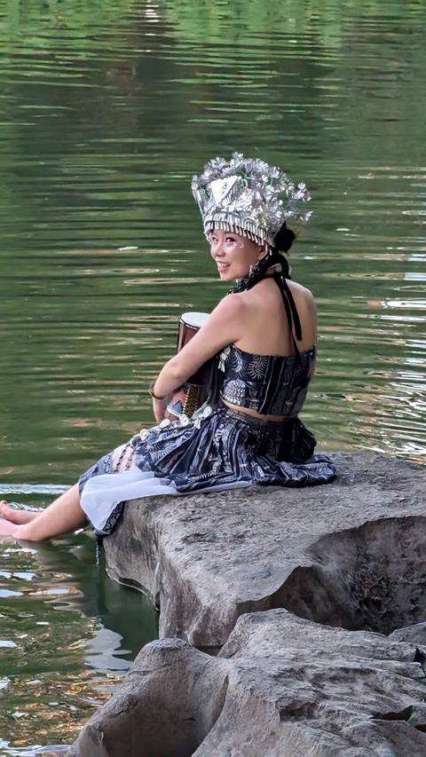 A person in a colorful traditional outfit by a river.