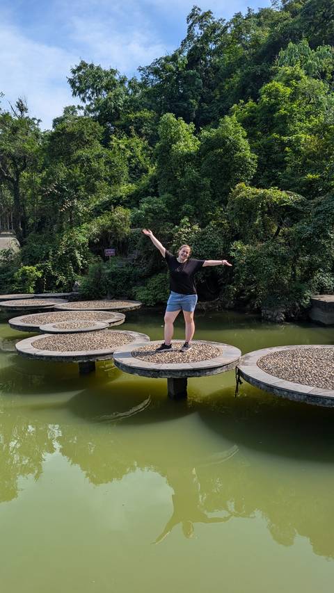       A person standing on circular stone platforms on water.
  