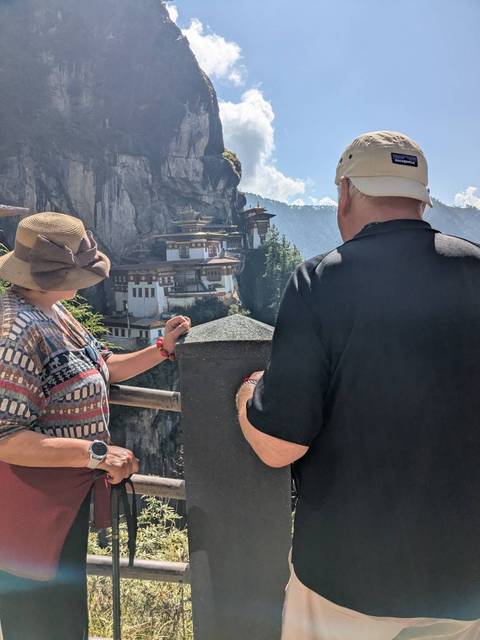       People looking at the Paro Taktsang monastery on a cliff.
  