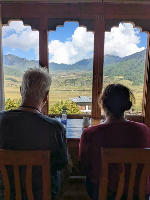       Two people sitting at a table with a scenic view from the window.
  