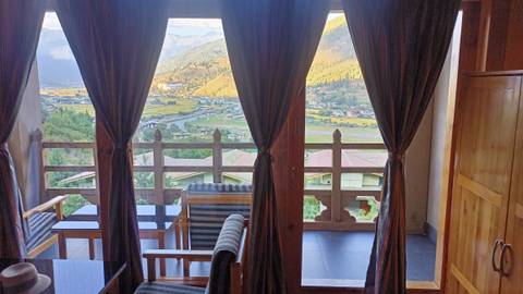 View through curtains showing a scenic valley and mountains
