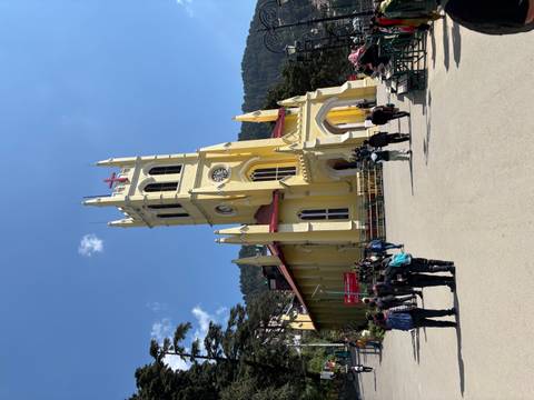 Yellow church with a red roof seen from below