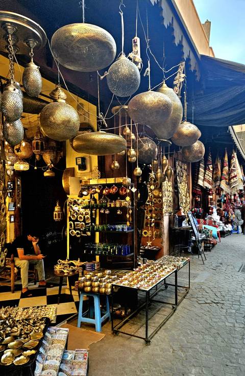 A bustling market scene with hanging lanterns and various metal crafts.