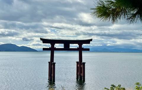       A torii gate in a lake with mountains in the background.
  