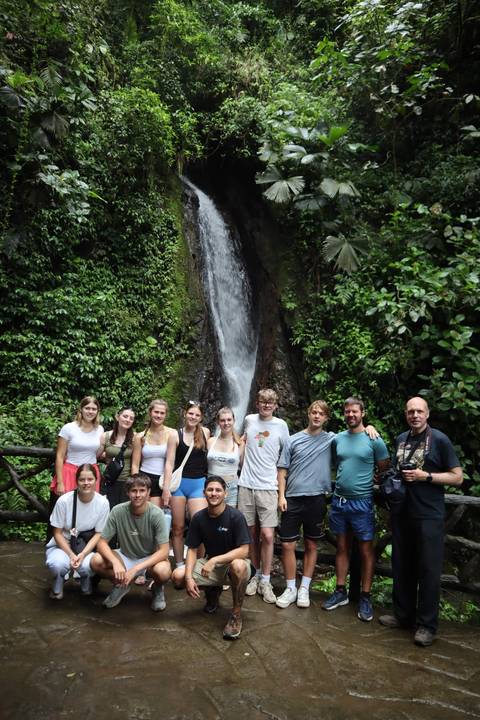 Group of people in front of a waterfall.