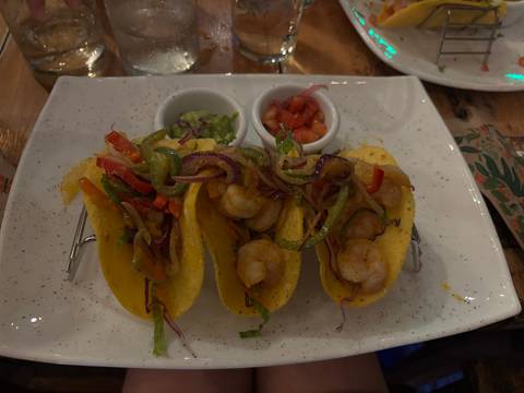 Plated shrimp tacos with sauces.