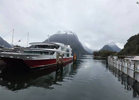       Ferry in a scenic fjord landscape with mountains.
  