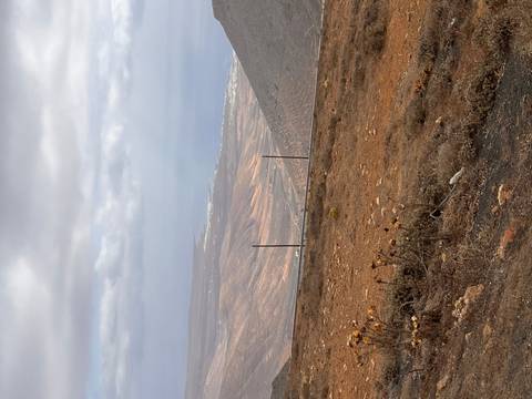       Hilly landscape with a road and sparse vegetation.
  