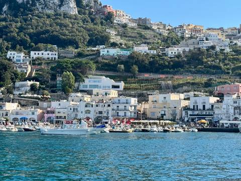 Coastal village with boats and hillside houses.