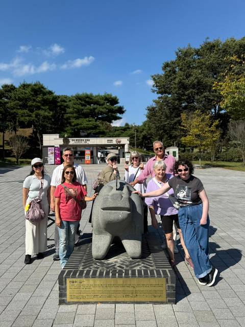 Group of people posing with a stone monument.