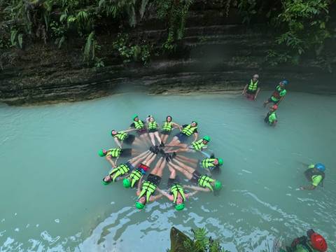       Group of people floating in a circle in a lagoon.
  
