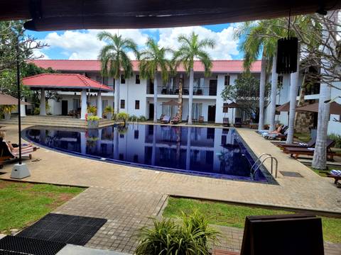 Hotel swimming pool with people relaxing around it.