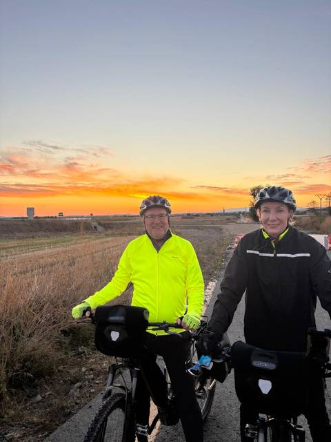       Cyclists at sunset on a rural road.
  
