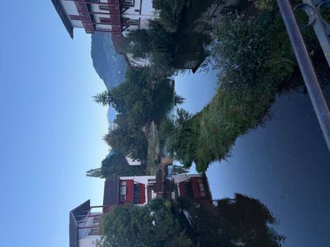       Buildings by a calm river under a clear sky.
  