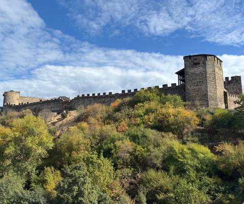       Stone fortress on a hill under a blue sky.
  